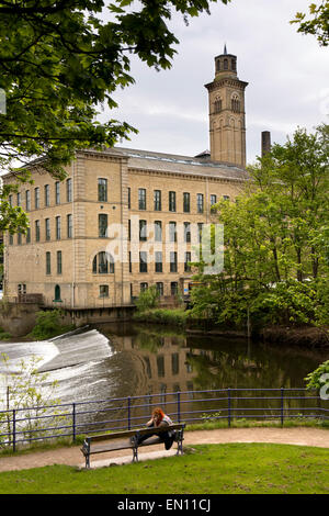 UK, England, Yorkshire, Saltaire, Robert’s Park, Salt’s New Mill beside weir on River Aire Stock Photo