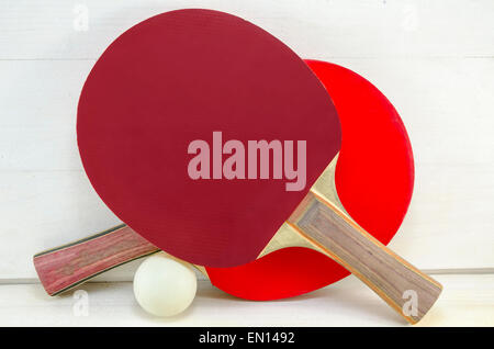 Two table tennis rackets and a ball on a wooden table Stock Photo