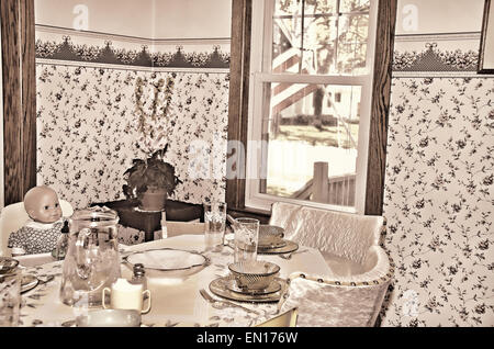 Old doll in a high chair in a retro kitchen. Stock Photo