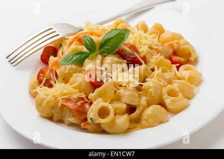 Gomiti rigata 'elbow' pasta tossed with tomatoes cooked in cream with green pesto, cherry tomatoes and grated parmesan. Stock Photo