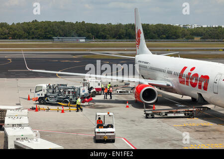 Boeing 737-900ER Air-side, airport servicing, staff loading passengers luggage into a plane hold using a conveyor belt system Stock Photo