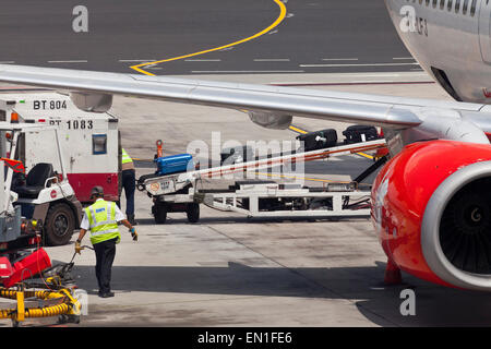 Air-side, airport servicing, staff loading passengers luggage into a plane hold using a conveyor belt system Stock Photo