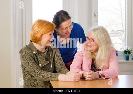 Close up Three Happy Middle Age Women Friends Enjoying their Girl Talk at the Wooden Dining Table Inside a Restaurant. Stock Photo