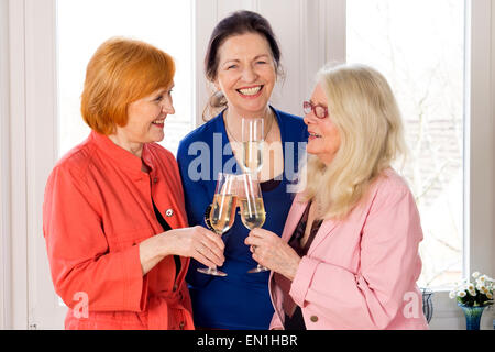 Close up. Three Reunited Mom Best Friends in Trendy Outfits Enjoying Glasses of White Wine. Stock Photo
