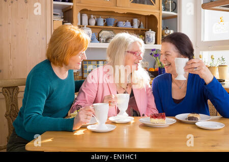 Three Cool Middle Age Female Friends Having Snacks at the Cafe While Talking Something Interesting. Stock Photo
