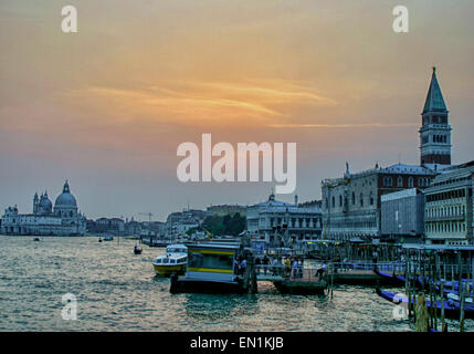 Oct. 7, 2004 - Venice, Province of Venice, ITALY - The sky is streaked with the glow of sunset over the waterfront of Venice. At left, in distance, the domes of Santa Maria della Salute basilica stand on the narrow finger of Punta della Dogana, between the Grand Canal and the Giudecca Canal. In center is the S.Zaccaria vaporetto dock.on the Basin of St Mark (Bacino di San Marco). At right, the gondola docks line the Riva Degli Schiavoni waterfront in front of the Palazzo Ducale (Doges Palace) with the top of the Campanile di San Marco (bell tower) rising above it. Venice is one of the most pop Stock Photo