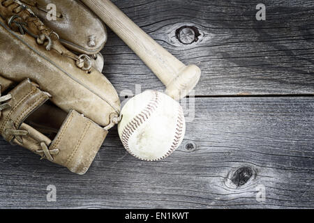 Vintage concept of  old worn glove, bat and used baseball on rustic wood Stock Photo