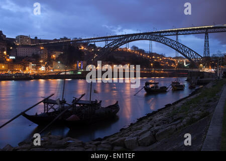 Porto, Portugal, Dom Luiz I Bridge and Rabelo boats on Douro river in the evening. Stock Photo