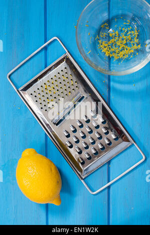 Lemon, bowl and grater on a blue board Stock Photo