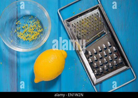 Lemon, bowl and grater on a blue board Stock Photo