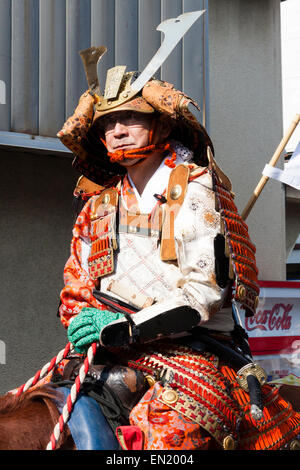 Japanese man dressed in full samurai armour and Kabuto helmet, on horseback riding through city street in the Genji parade at Tada in Japan. Stock Photo