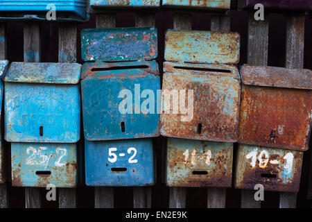 Four old mailboxes with rust attached to the fence Stock Photo