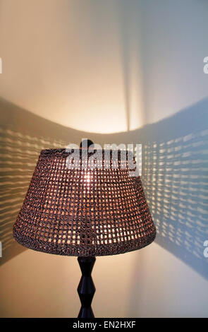 Wicker lamp in a bedroom with shadows on the wall Stock Photo