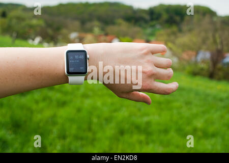 Ostfildern, Germany - April 26, 2015: A middle aged Caucasian woman is checking her Apple Watch displaying the home screen with Stock Photo