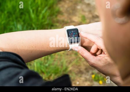 Ostfildern, Germany - April 26, 2015: A middle aged Caucasian woman is checking her Apple Watch displaying the main screen with Stock Photo