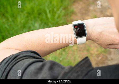Ostfildern, Germany - April 26, 2015: A middle aged Caucasian woman checking her Apple Watch displaying her pulse while walking Stock Photo