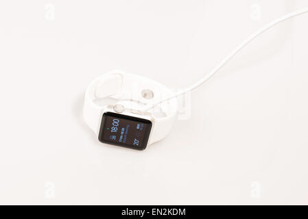 Ostfildern, Germany - April 26, 2015: Charging the new Apple Watch: A white 38mm Apple Watch Sport being charged using MagSafe Stock Photo