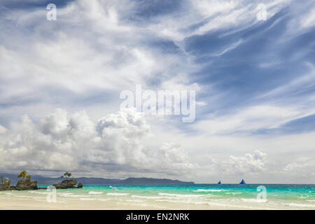 Blue sailing boat on horizon of hot blue tropical sea big white clouds on blue sky, yellow sand beach Philippines Boracay island Stock Photo