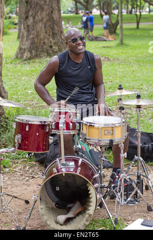 SAO PAULO, BRAZIL - FEBRUARY 01, 2015: An unidentified street musician singing and playing drums in the Ibirapuera Park at Sao P Stock Photo