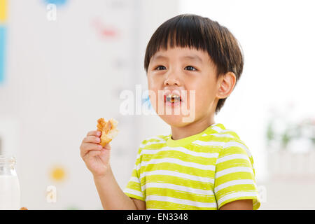 The little boy eat bread in the kindergarten Stock Photo