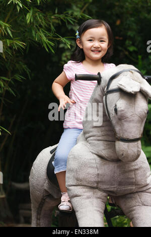 Cute little girl riding rocking horse Stock Photo