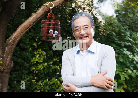 An elderly man with arms crossed in the yard Stock Photo