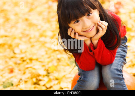 Beautiful little girl sitting on the pumpkin Stock Photo