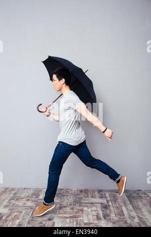 Asian man walking with umbrella in studio Stock Photo