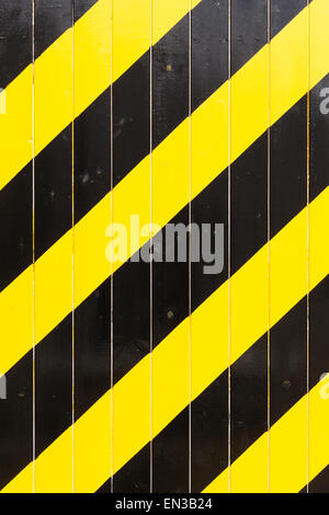 Full frame black and bright yellow diagonal warning stripes painted on an industrial wooden door. Stock Photo