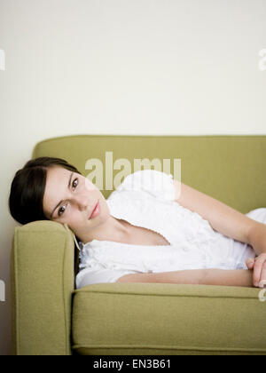 Young woman lying on sofa at home Stock Photo - Alamy