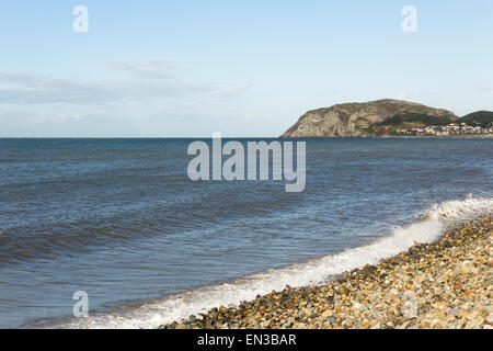 A fairly calm sea washes up on the shingle beach at Llandudno, North Wales with Little Orme in the background. Stock Photo