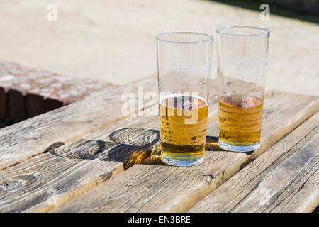 Two half empty glasses of beer or shandy on a wooden pub table, glasses marked Seafarer's Ale Stock Photo