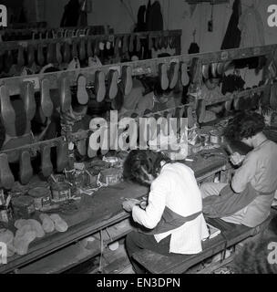 1950s historical, female asian workers sitting at workbenches making light Chinese rubber sole shoes, with synthetic fabric tops, Hong Kong. These slip-on soft shoes, known as the 'Kung-Fu' shoe, as they were originally use for martial arts, are traditionally made in workshops in China and other parts of Asia. Such footwear is also known as a martial arts slipper or 'Tai Chi' shoe. Stock Photo