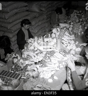 1950s, historical, hong kong, female chinese workers in a factory unit, siting, putting together plastic toy dolls. It was not long after the end of WW2, that hard plastic became the material for doll makers to use, as it was durable and could be molded. Hong Kong soon became an epicentre for toy production in the 50s and 60s, with thousands of small-scale manufacturing and production units like the one seen here established in basements and upper-floors of buildings. Stock Photo