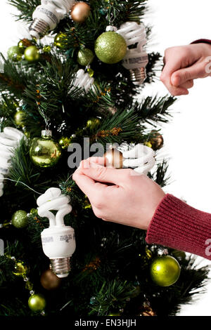 Young woman decorating Christamas tree with energy efficient lightbulbs Stock Photo