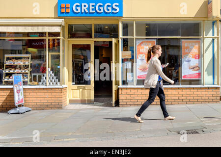 Chippenham, UK. 27th April, 2015. A pedestrian is pictured walking past a Greggs outlet in Chippenham,Wiltshire. Greggs plc is the largest bakery chain in the United Kingdom, with 1,671 outlets and is due to announce it's latest trading update on Wednesday 29th April. Credit:  lynchpics/Alamy Live News Stock Photo