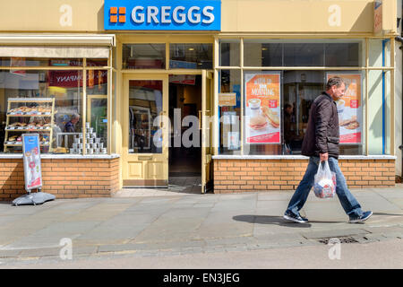 Chippenham, UK. 27th April, 2015. A pedestrian is pictured walking past a Greggs outlet in Chippenham,Wiltshire. Greggs plc is the largest bakery chain in the United Kingdom, with 1,671 outlets and is due to announce it's latest trading update on Wednesday 29th April. Credit:  lynchpics/Alamy Live News Stock Photo