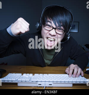 Man with headset making fists and sitting at keyboard Stock Photo
