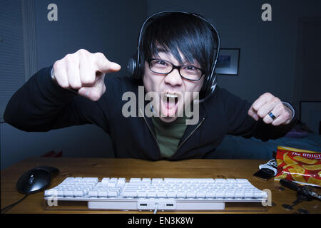 Man with headset making fists and sitting at keyboard Stock Photo