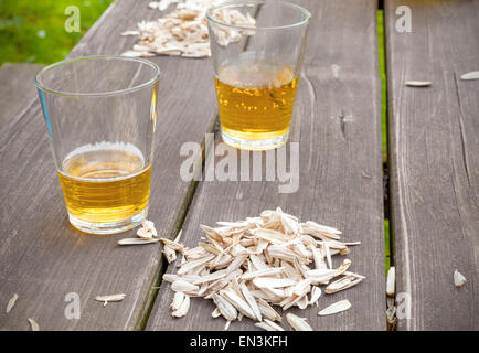 Sunflower seed husks and two glasses on the garden table, summer snack concept. Stock Photo