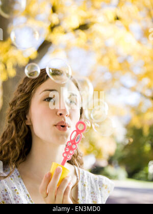 Young woman blowing soap bubbles in Autumn forest Stock Photo
