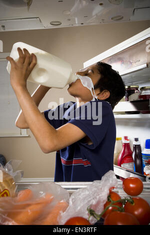 Boy drinking milk from jug and spilling on face Stock Photo