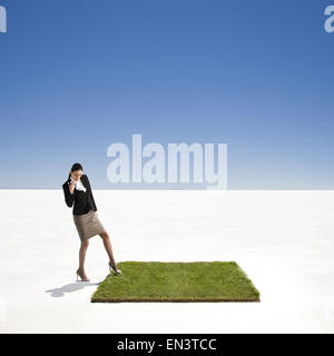businessperson on a patch of green grass in the middle of the desert Stock Photo