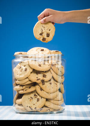 Hand grabbing chocolate chip cookie from jar Stock Photo - Alamy