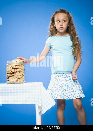 Girl sneaking Chocolate Chip Cookie from cookie jar Stock Photo