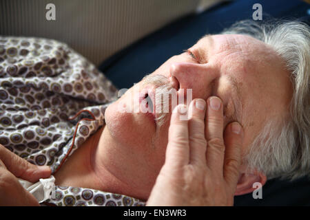 A senior man suffers the miseries of the flu while lying on a sofa. Stock Photo