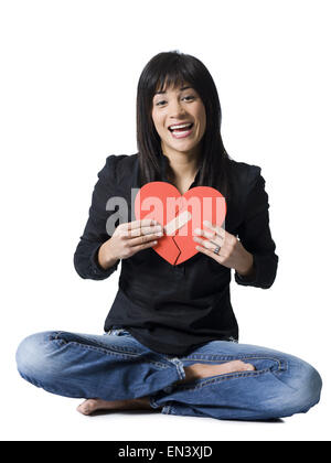 Woman sitting cross legged with mended red heart smiling Stock Photo