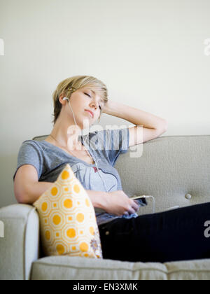 woman sitting on couch listening to an iPod Stock Photo