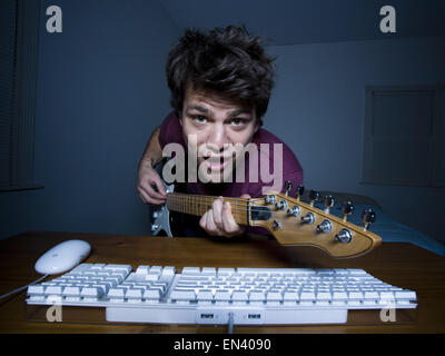 Man at keyboard playing guitar and singing Stock Photo