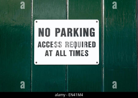White No Parking sign with black text on green painted background Stock Photo